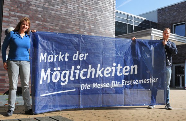 Ein Mann und eine Frau halten ein blaues Banner hoch.