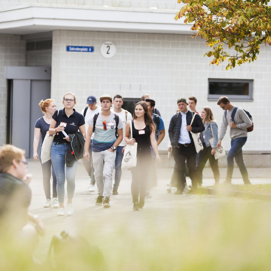 eine Gruppe junger Menschen schlendert über den Campus der FH Kiel. 