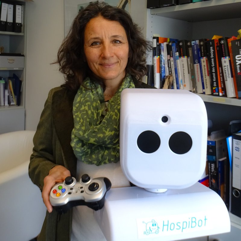 Professor Dr. Franziska Uhing steht an dem von ihr progrmamierten Roboter