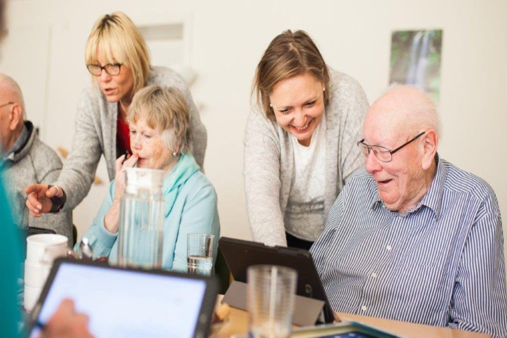 Senioren bekommen von älteren Menschen erklärt, wie Tablets funktionieren