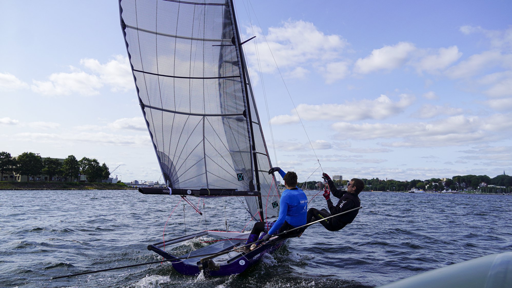 Zwei junge Männer segeln auf der Kieler Förde.