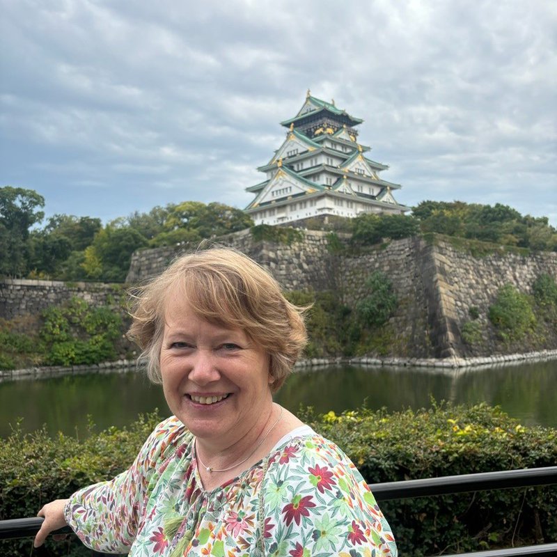 Doris Weßels steht am Ufer eines Gewässers, dahinter das Schloss in Osaka