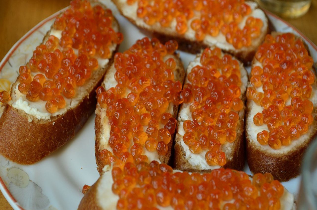 Mit Butter und orangenem Kaviar belegte Häppchen.