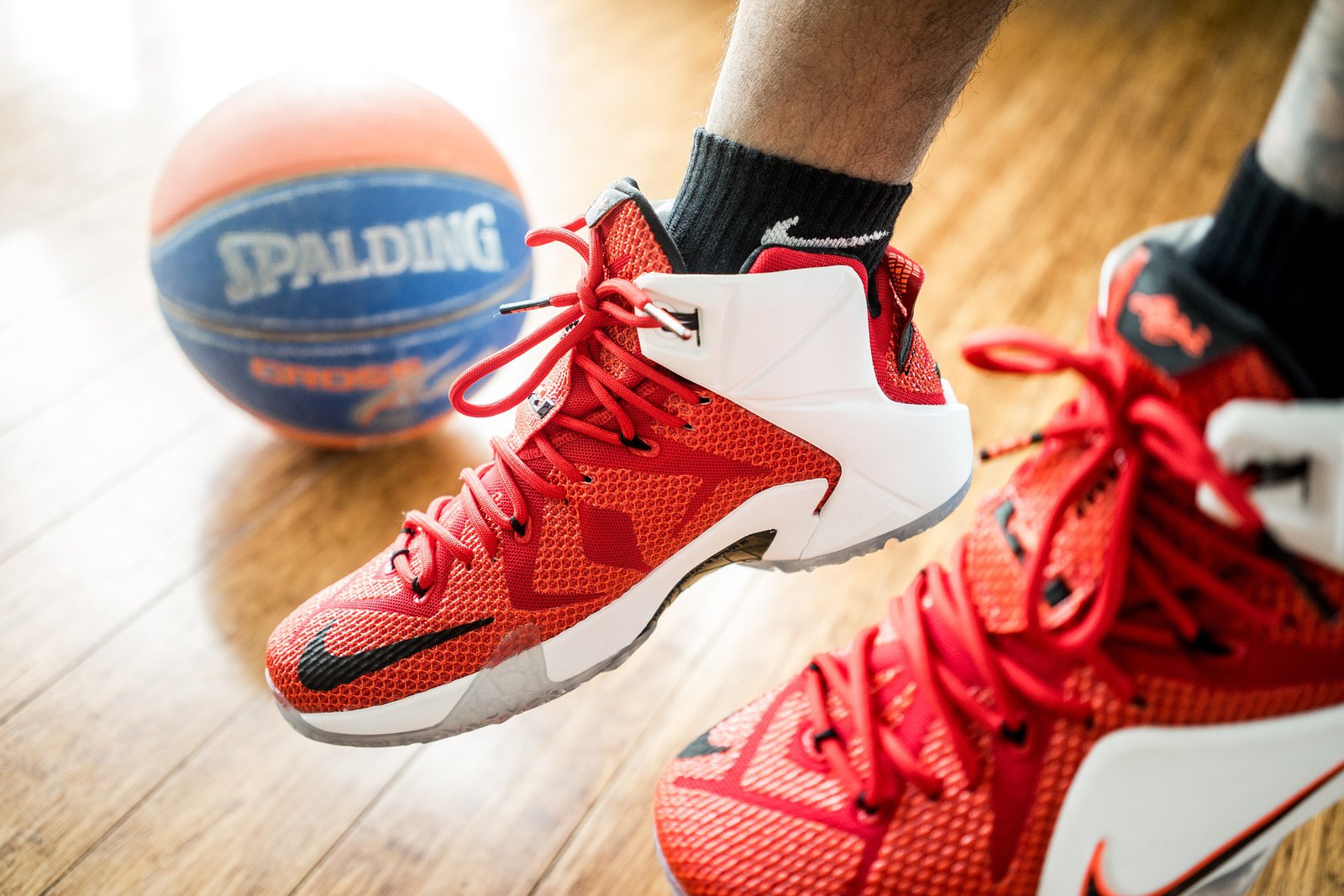 Ein Paar männer Füße bekleidet mit Sportschuhen, im Hintergrund ist ein Basketball zu sehen.