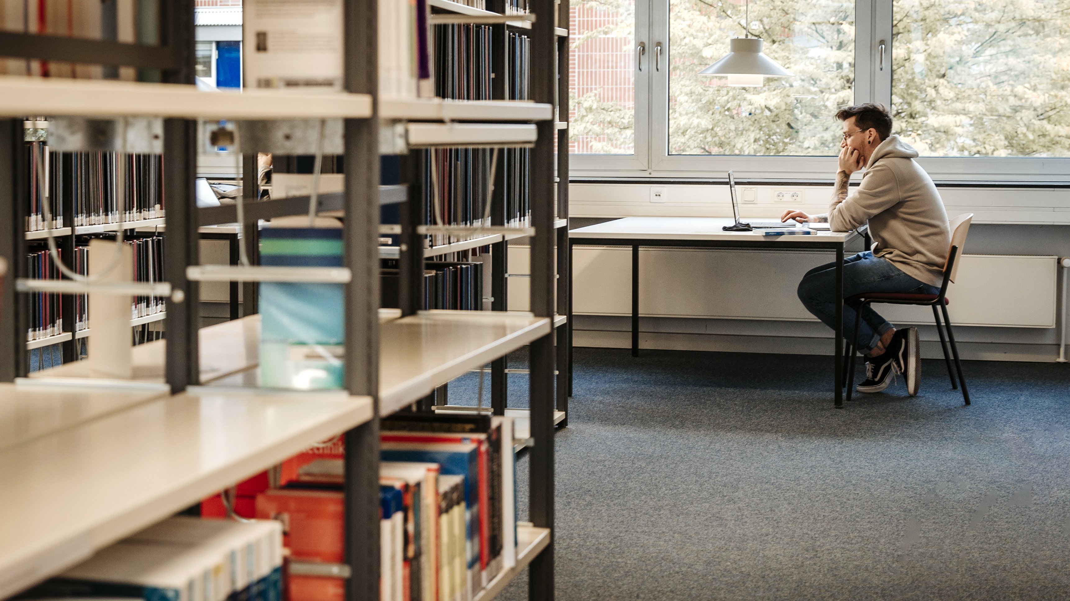 Mann sitzt in Bibliothek.