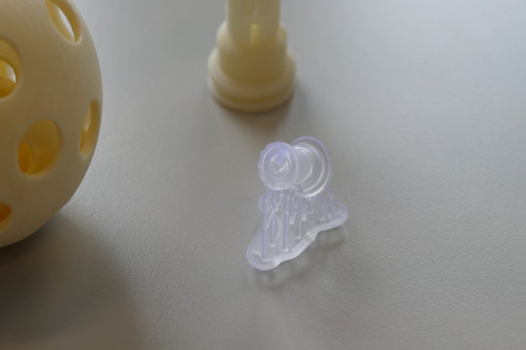 Drei aus dem 3D-Drucker stammende  Gegenstände. Zwei von ihnen sind eher gelblich, einer von ihnen ist nahe zu weiss-transparent.