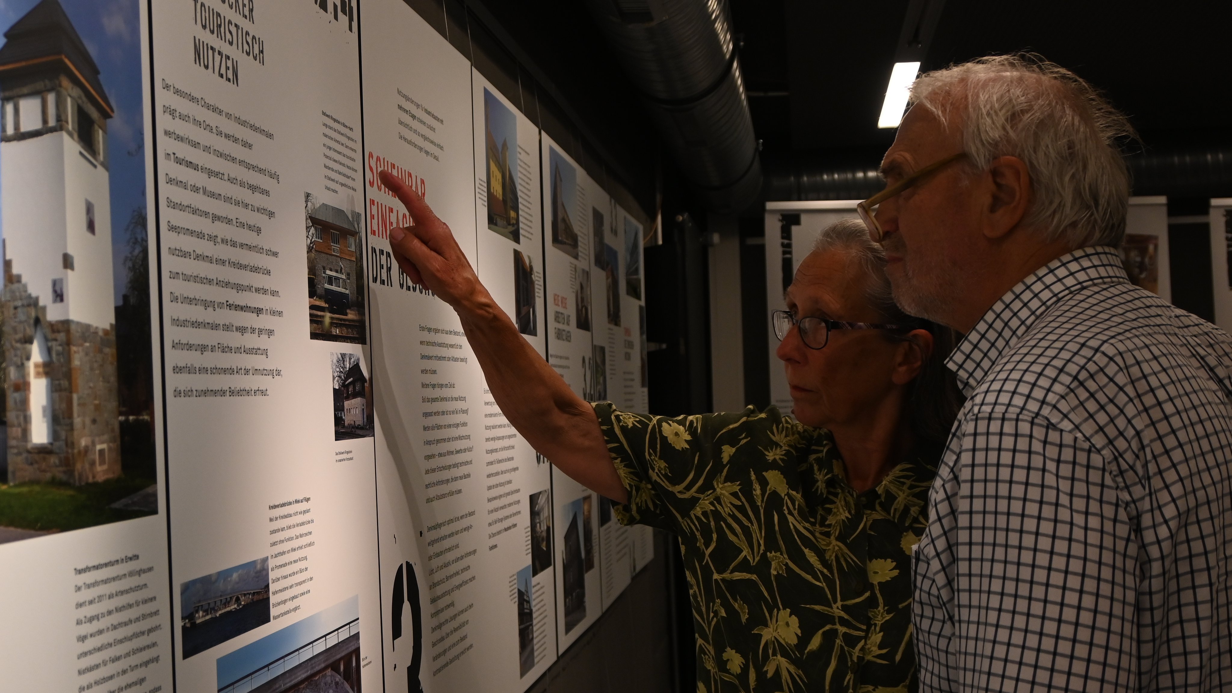 Ehepaar schaut sich Infos auf Tafeln der Ausstellung an