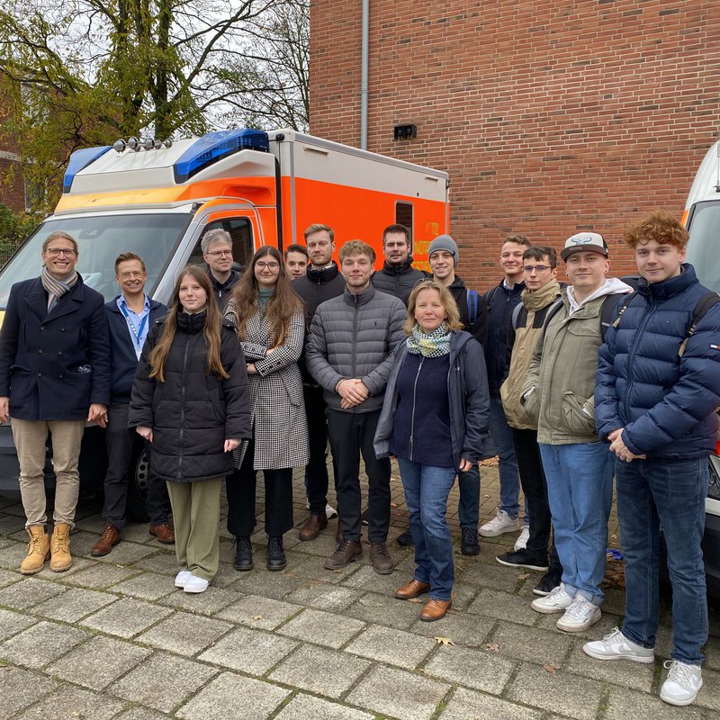 Eine Gruppe steht zwischen zwei Rettungswagen.