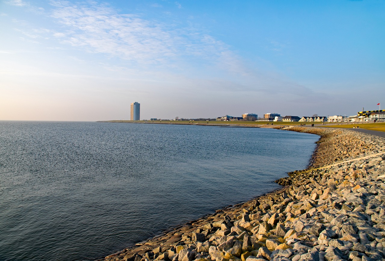 Die Büsumer Bucht zur linken, der Deich zur rechten. Im Hintergrund sieht man ein Hochhaus.