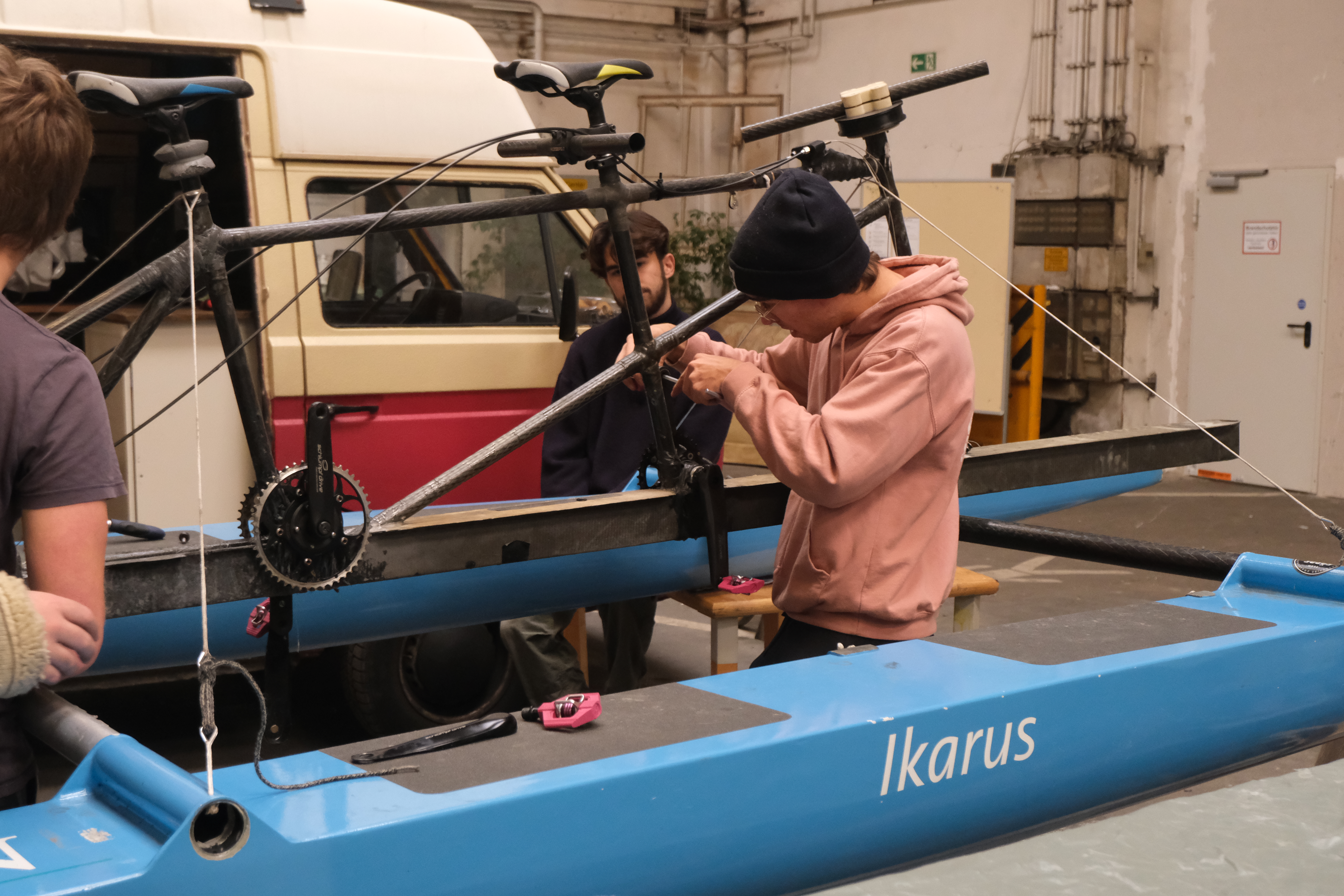 Ein Fahrradähnliches Gerüst steht im Mittelpunkt des Bildes. Ein Student justiert etwas an dem Rahmen des Gefährtes.