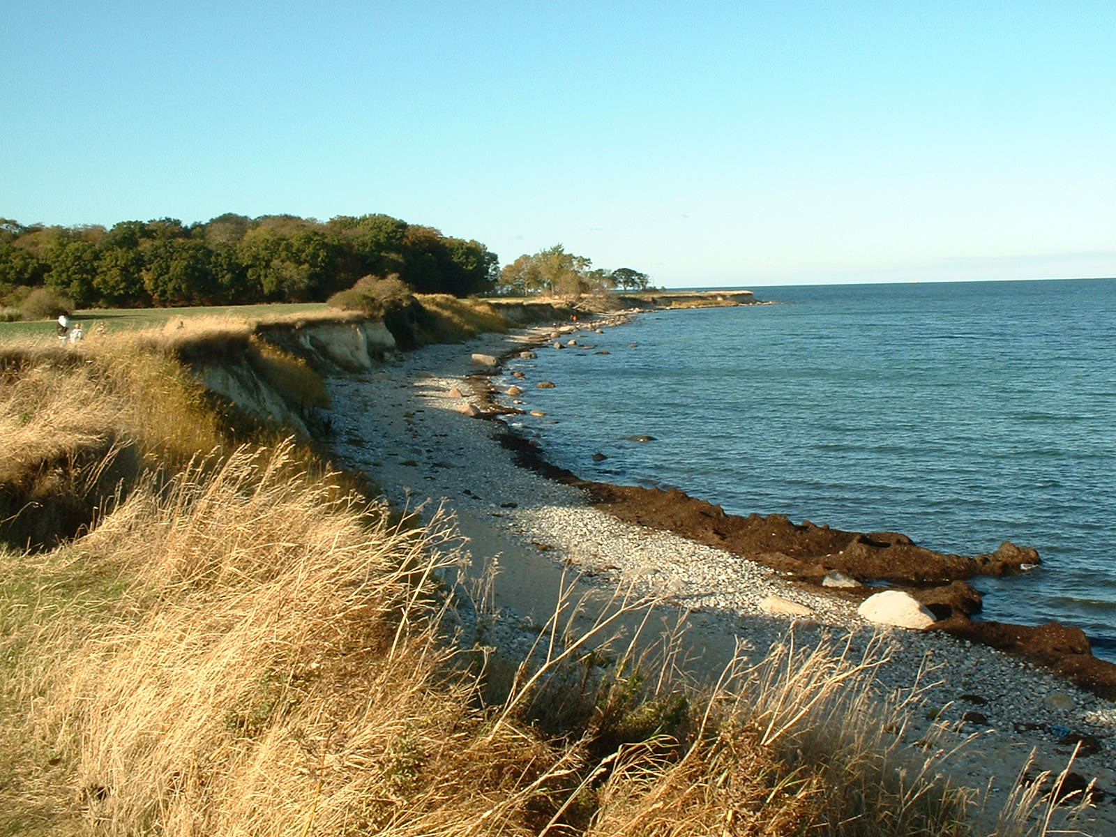 Ostseeküste. Die Sonne scheint von links auf die Dünenlandschaft vor der Küste.