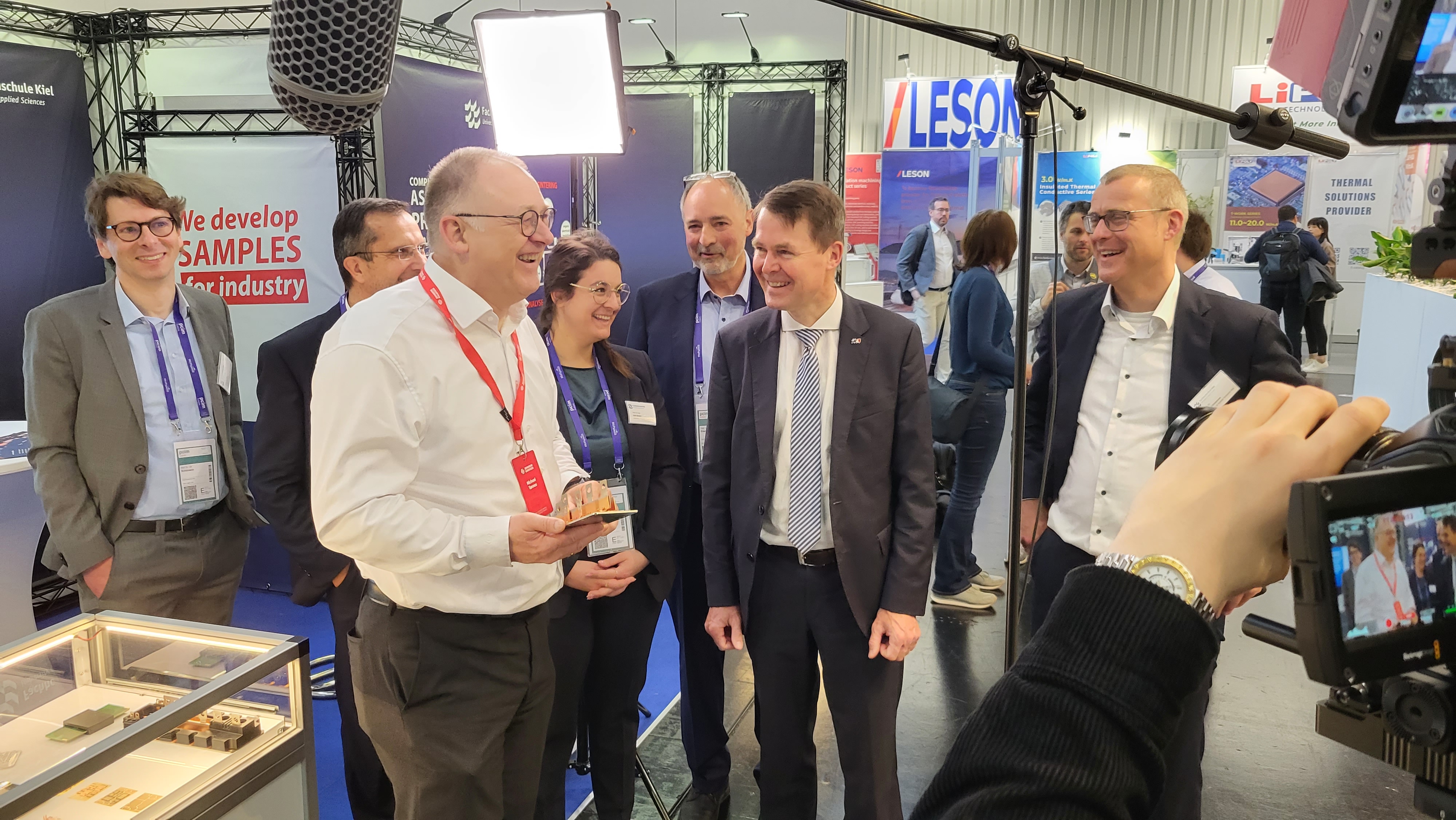 eine Gruppe von Menschen steht um ein elektronisches Bauteil herum auf der PCIM-Messe in Nürnberg