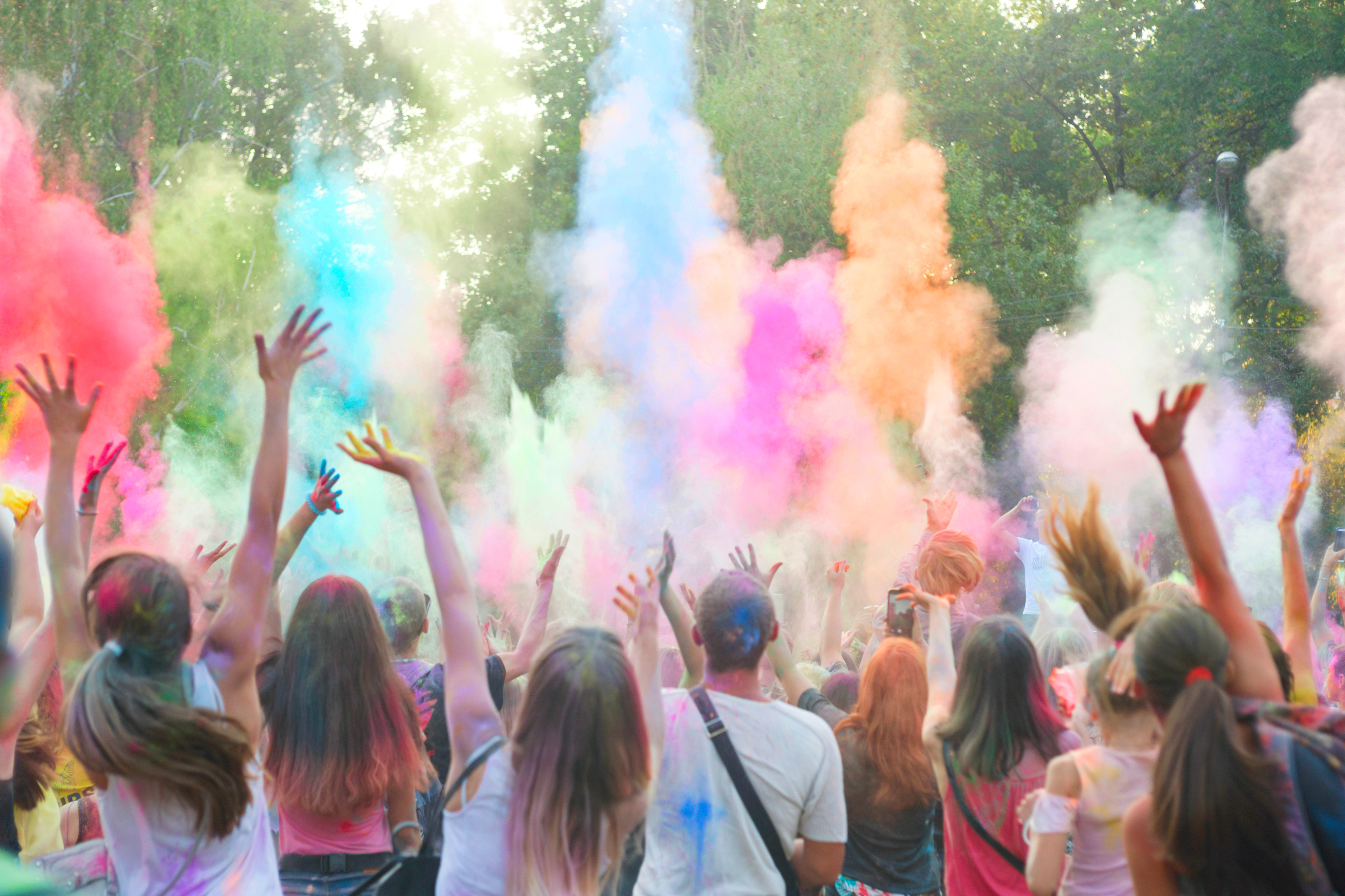 eine Gruppe von Menschen wirft buntes Farbpulver beim Holi-Festival in die Luft