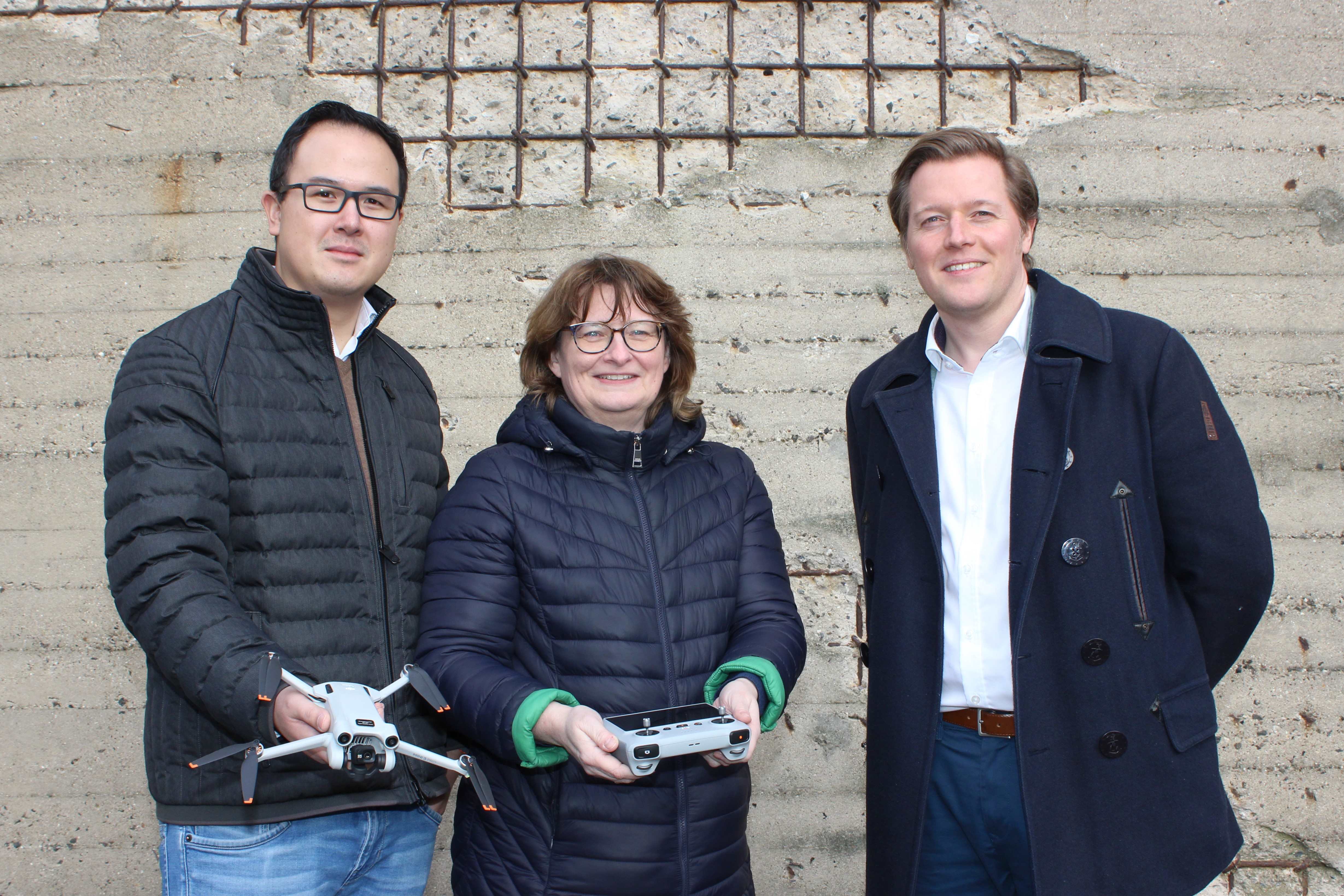 drei Personen stehen mit einer Drohne vor dem Bunker-D an der FH Kiel