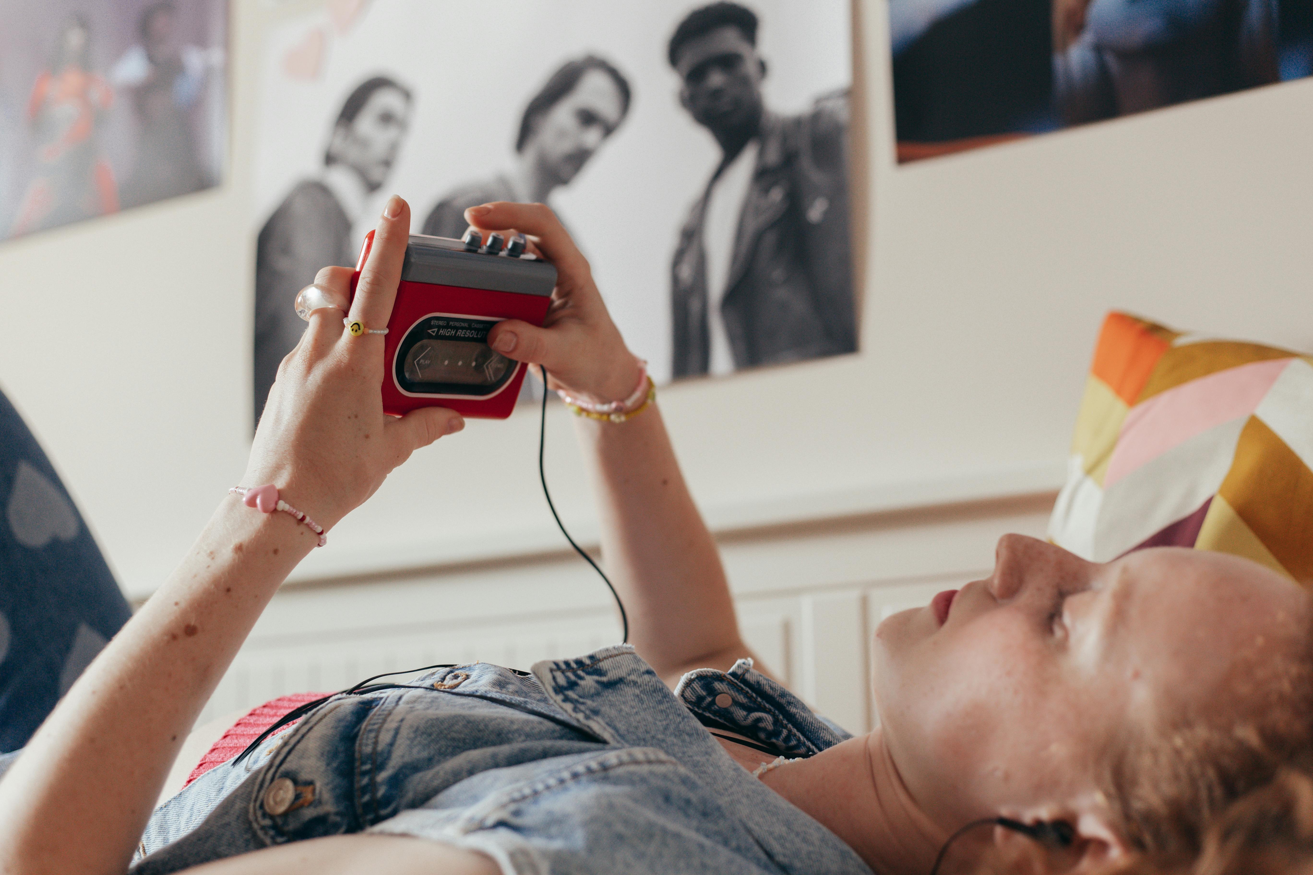 Frau liegt auf Bett und hört Musik auf ihrem Walkman.