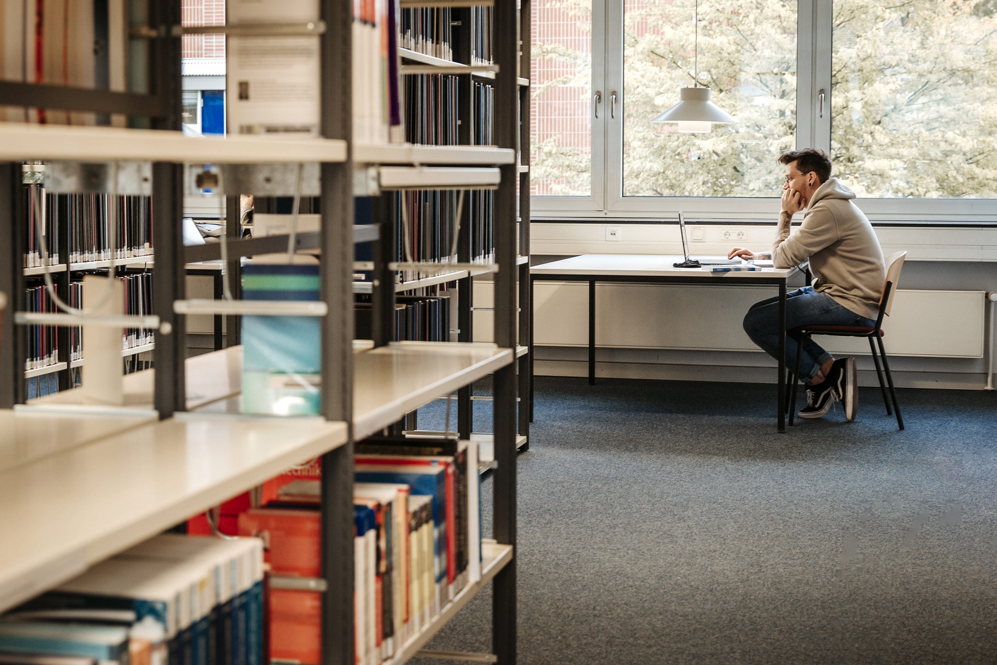 Mann sitzt in Bibliothek.