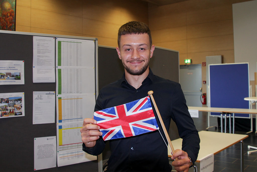 Ein Mann posiert mit einem Wimpel der englischen Flagge in den Händen.